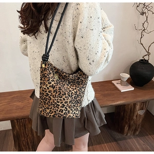 Detailed view of a leopard print bucket bag featuring a cylindrical strap and gold charm