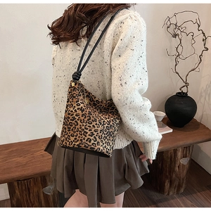 Detail of leopard print bucket bag featuring a drawstring strap and metal chain pendant