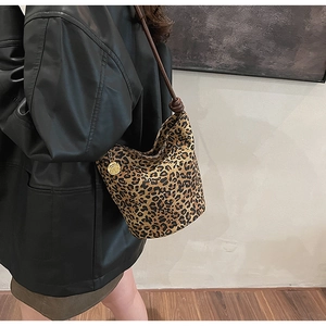 Detailed view of leopard print bucket bag with gold flower charm and rope strap