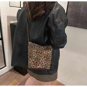 Detail of leopard print bucket bag with gold chain and vintage metal pendant on a model