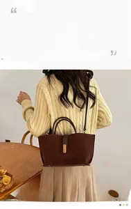 Detail of dark brown suede handbag featuring gold buckle on a yellow sweater background
