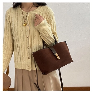 Detail of dark brown suede tote with gold buckle and leather strap on model