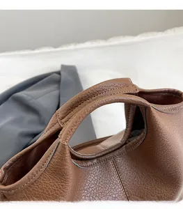 Macro detail of brown bucket bag with lychee texture leather and fine stitching finish
