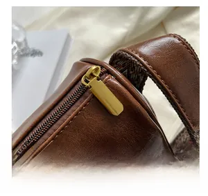 Détail de la fermeture dorée sur sac en cuir marron avec bandoulière tissée