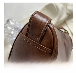 Détail montrant les coutures de qualité et la texture en cuir marron du sac à bandoulière