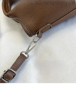 Close-up of brown litchi grain leather bag with polished silver metal buckle and strap