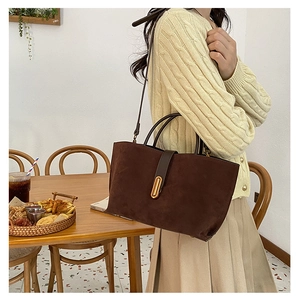 Detail of vintage suede bucket bag in dark brown with elegant gold metal buckle closure