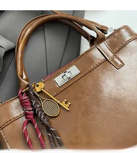 Détails d'un sac à main en cuir marron vintage avec fermoir rotatif argenté et breloques