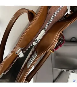 Vue détaillée du dessus d'un sac à main en cuir marron foncé avec fermeture éclair argentée