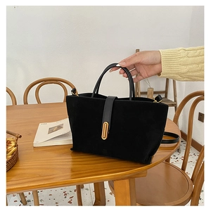 Close-up of black suede tote bag with gold rings on wood table for daily use