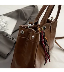 Gros plan d'un sac à main marron avec boucle argentée et pendentif en corde tressée