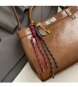 Détail d'un sac en cuir marron avec fermoir argenté et breloques décoratives rétro