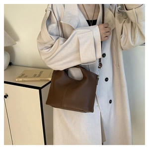 Deep brown litchi pattern leather crossbody bag styled with a beige trench coat