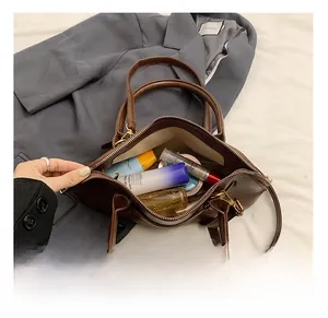 Internal view of the large capacity brown leather bag showing cosmetics and golden zipper