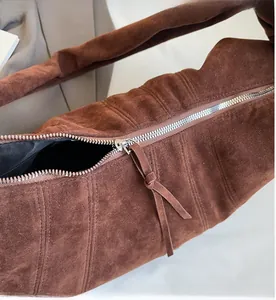 Detail of smooth silver zipper and long leather puller on brown suede hobo bag