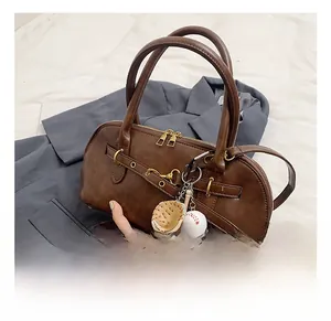 Detail of vintage brown shoulder bag with gold hardware and baseball themed charms