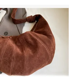 Detail view of brown suede croissant bag with pleat stitching and knotted shoulder strap