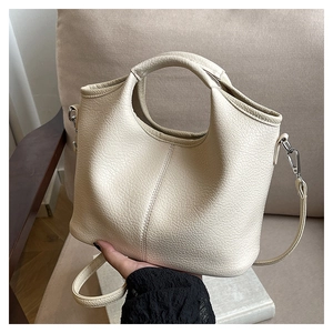 Detail of cream bucket bag showing lychee grain texture and silver metal hardware