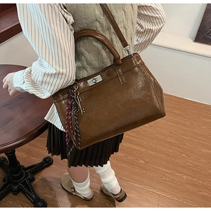 Détail du sac vintage en cuir marron avec fermoir tournant argenté et ruban de soie