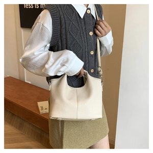 Detail of beige lychee texture hobo bag with adjustable strap shown on shoulder