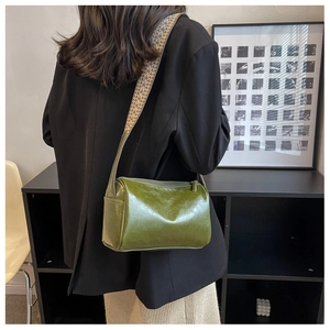 Macro view of vintage green leather crossbody bag featuring wide geometric woven strap