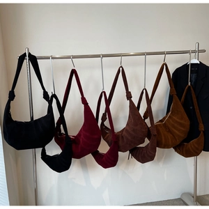 Detail view of suede croissant bags in various colors and sizes hanging on a rack