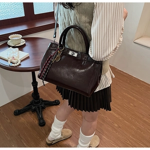 Détail d'un sac cabas vintage en cuir marron avec fermoir rotatif et pendentif