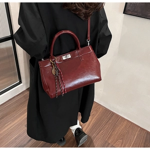 Détails du sac à main rouge foncé en cuir verni avec fermoir argenté et breloque tressée