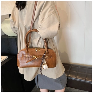 Retro brown shell tote bag with decorative straps and baseball charm in lifestyle setting