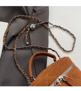 Detail of brown suede quilted chain bag with silver zipper and woven shoulder strap
