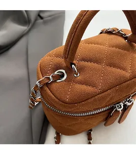 Macro view of caramel brown quilted bucket bag with silver chain strap and top handle