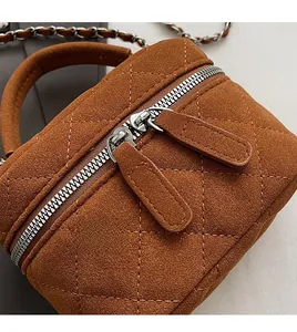 Detail of smooth double zipper and quilted suede texture on the brown chain crossbody bag