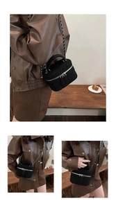 Detail of black quilted velvet mini bucket bag with silver chain strap and top handle