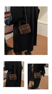 Detail of brown suede mini crossbody bag with quilted texture and silver chain strap