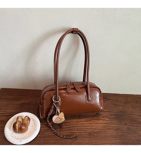 Detail of brown vintage baguette bag with contrast stitching and baseball charm