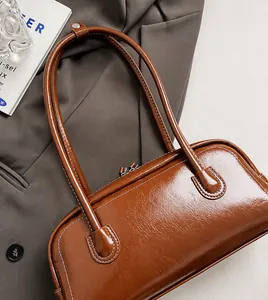 Detail of glossy brown leather shoulder bag with dual metal zippers and smooth straps