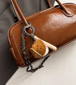 Detail of baseball theme charm with leather glove and wooden bat on a vintage brown bag