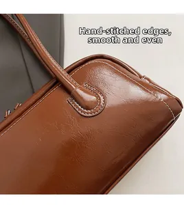 Detail of high-gloss oiled leather underarm bag with white contrast hand-stitching
