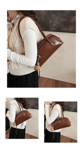 Close-up of vintage brown baguette bag with glossy texture and cute doll pendant detail