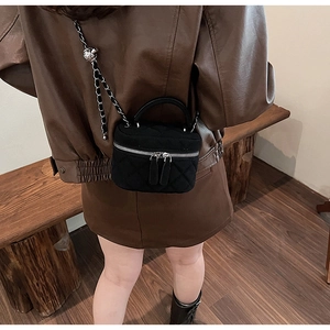 Close-up of black quilted suede mini crossbody bag with silver chain and dual zippers