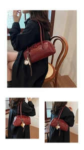 Detail of burgundy baguette bag featuring dual zippers and a baseball themed keychain charm