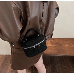 Close-up of quilted suede mini crossbody bag with silver chain and dual zipper detail