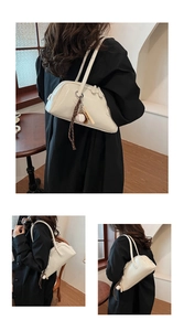 Detail of cream baguette bag with vintage finish and unique baseball bat keychain