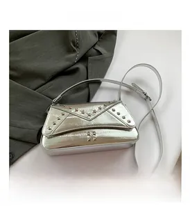 Detail of silver metallic crossbody bag featuring square rivets and adjustable strap