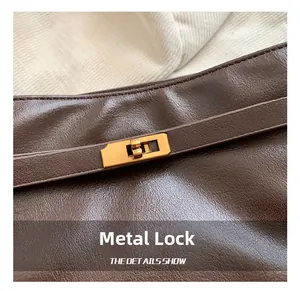 Close-up of golden rectangular twist-lock hardware on brown litchi pattern leather bag