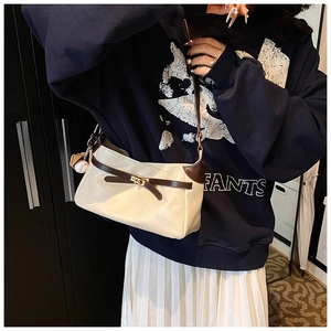 Detail of beige PU leather baguette bag with brown trim and vintage baseball pendant charm