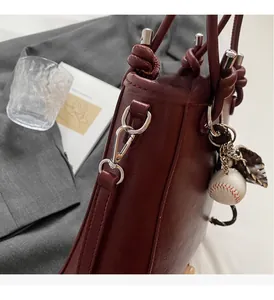 Close-up of luxury burgundy bucket bag with silver hardware and creative charm