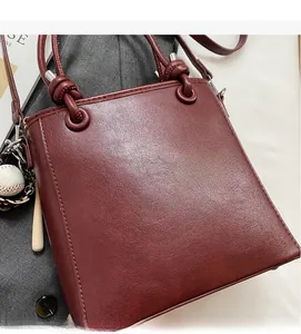 Detailed macro view of dark red leather bucket bag with baseball bat charms and soft texture