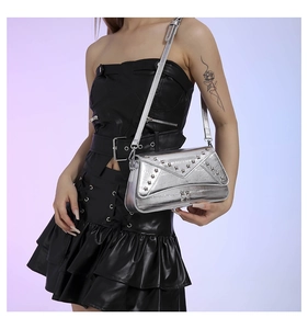 Detail of silver metallic shoulder bag with star rivets worn by a model in studio