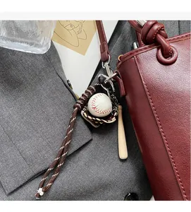 Detail of baseball theme charm with wooden bat and leather glove on a burgundy handbag